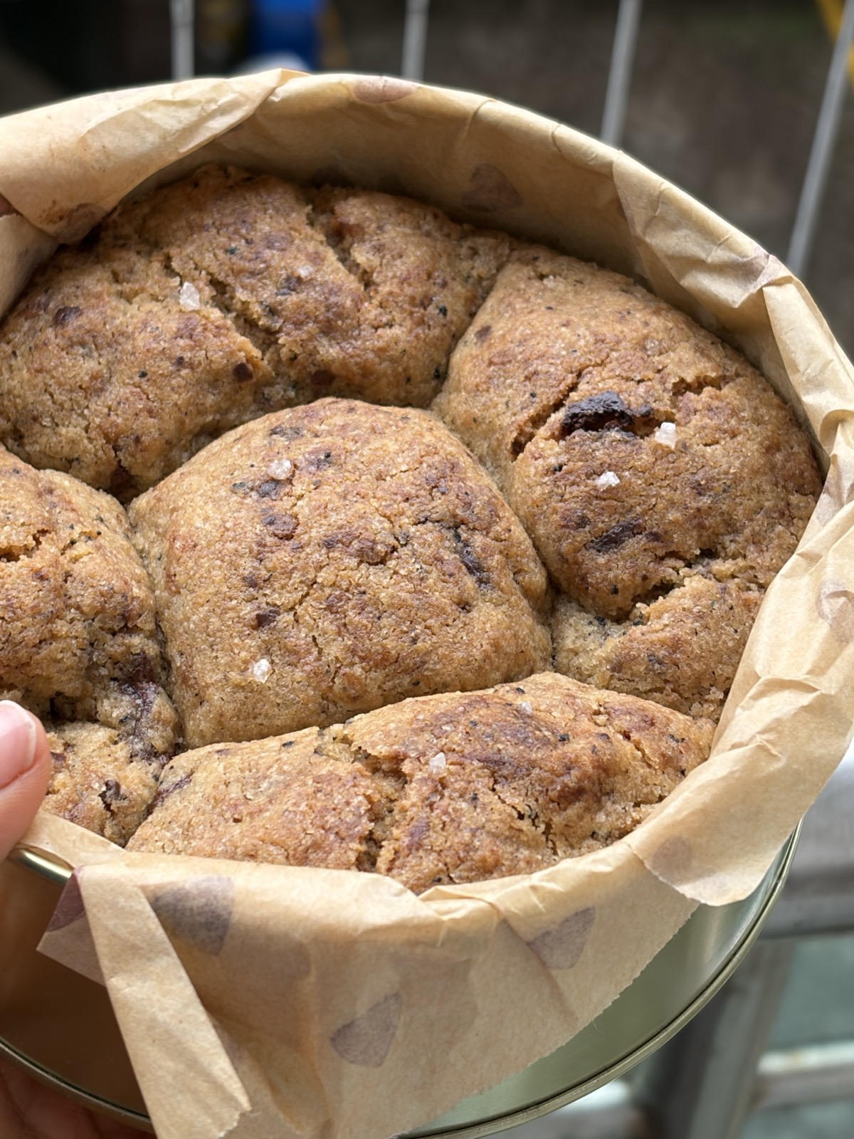 Brown butter chocolate cookies baked in a round tin lined with heart-printed paper, held in a hand